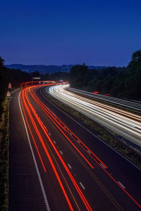 Traffic moving along a tree-lined motorway at night