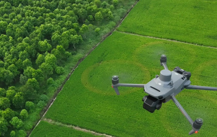 A survey drone flying over tree-lined fields, collecting aerial imagery